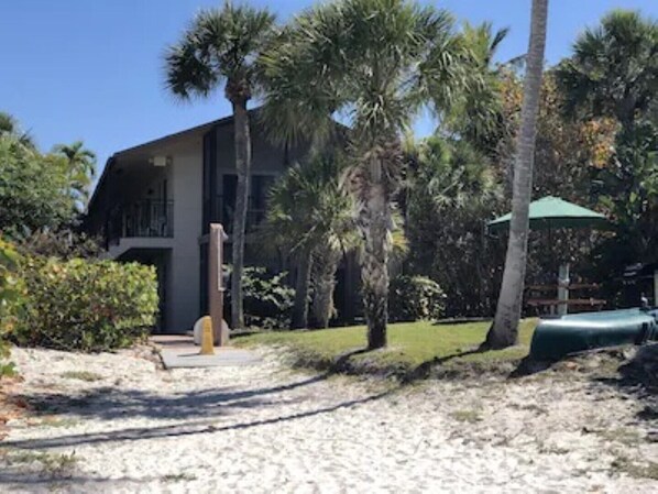 A building with a modern architectural style, surrounded by palm trees and a well-maintained lawn. - Beach Resort- First Floor walkout to Sand! (Fort Myers Beach)