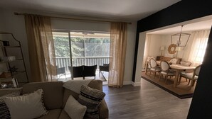 Ein Wohnzimmer mit einer Couch, einem Essbereich mit Tisch und Stühlen sowie ein Balkon mit Geländer.