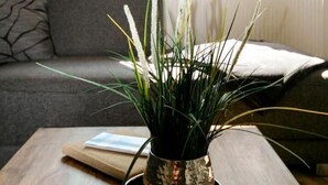 Un salon avec une table basse en bois, un canapé gris et une plante en pot.