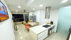 A modern kitchen with a central island, a dining area with a table and chairs, and a large window providing a view of the cityscape. - Exclusive Apartment 3 Bedroom in Beach Club (Santa Marta)