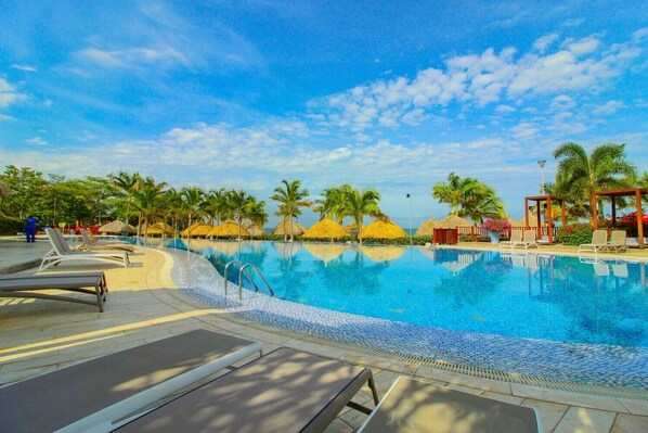 A swimming pool with lounge chairs and palm trees.