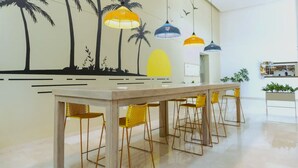A modern kitchen with a long island counter, yellow chairs, and pendant lights. - Exclusive Apartment 3 Bedroom in Beach Club (Santa Marta)