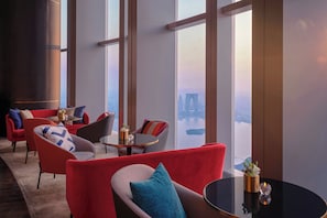 A modern hotel lobby with red sofas, a round table, and large windows offering a city view. - Niccolo Suzhou (Suzhou)