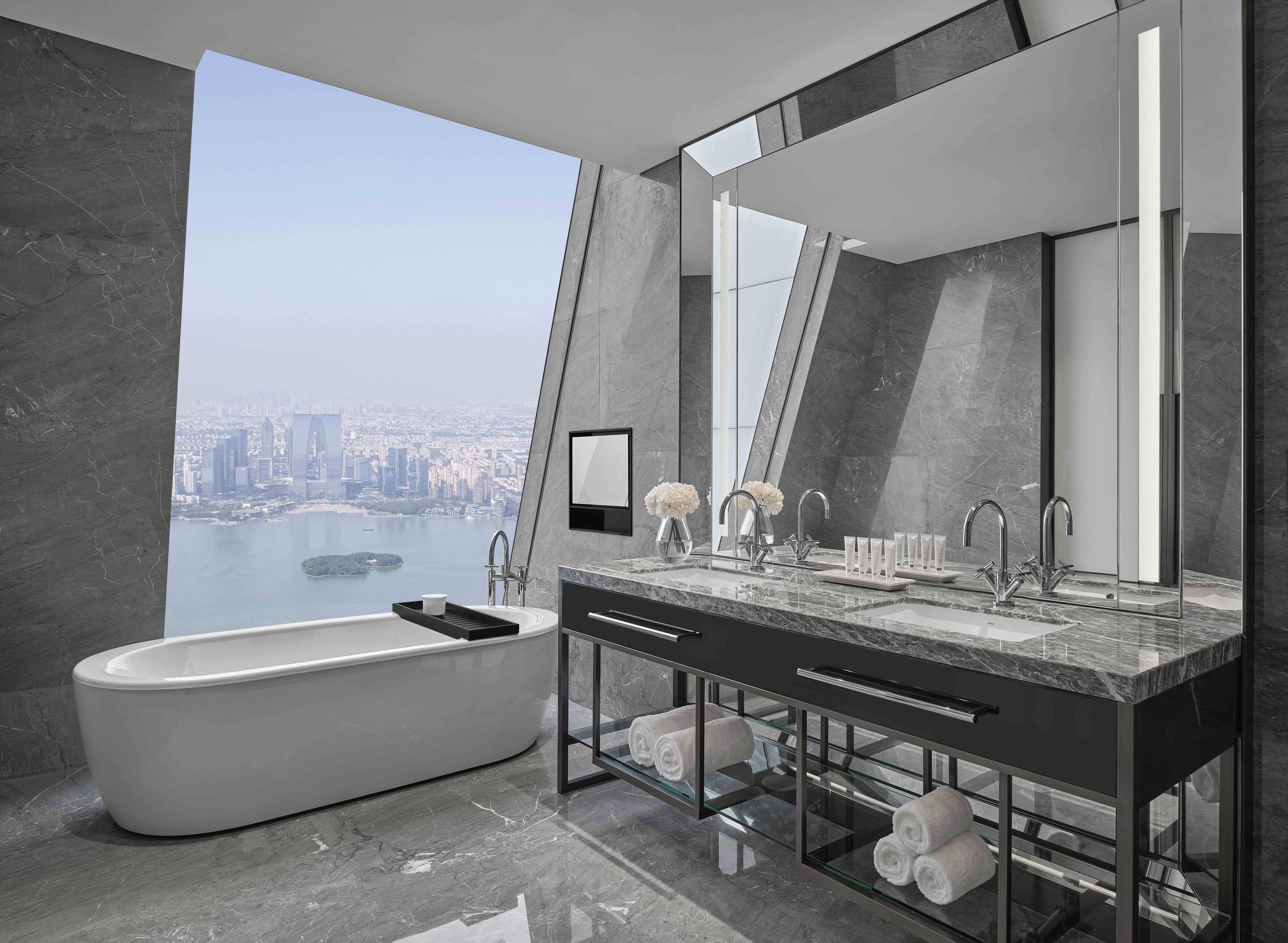 A modern bathroom with a bathtub, dual sinks, and a large mirror.