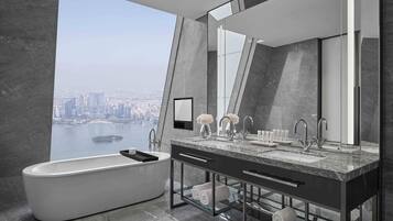 A modern bathroom with a bathtub, dual sinks, and a large mirror.