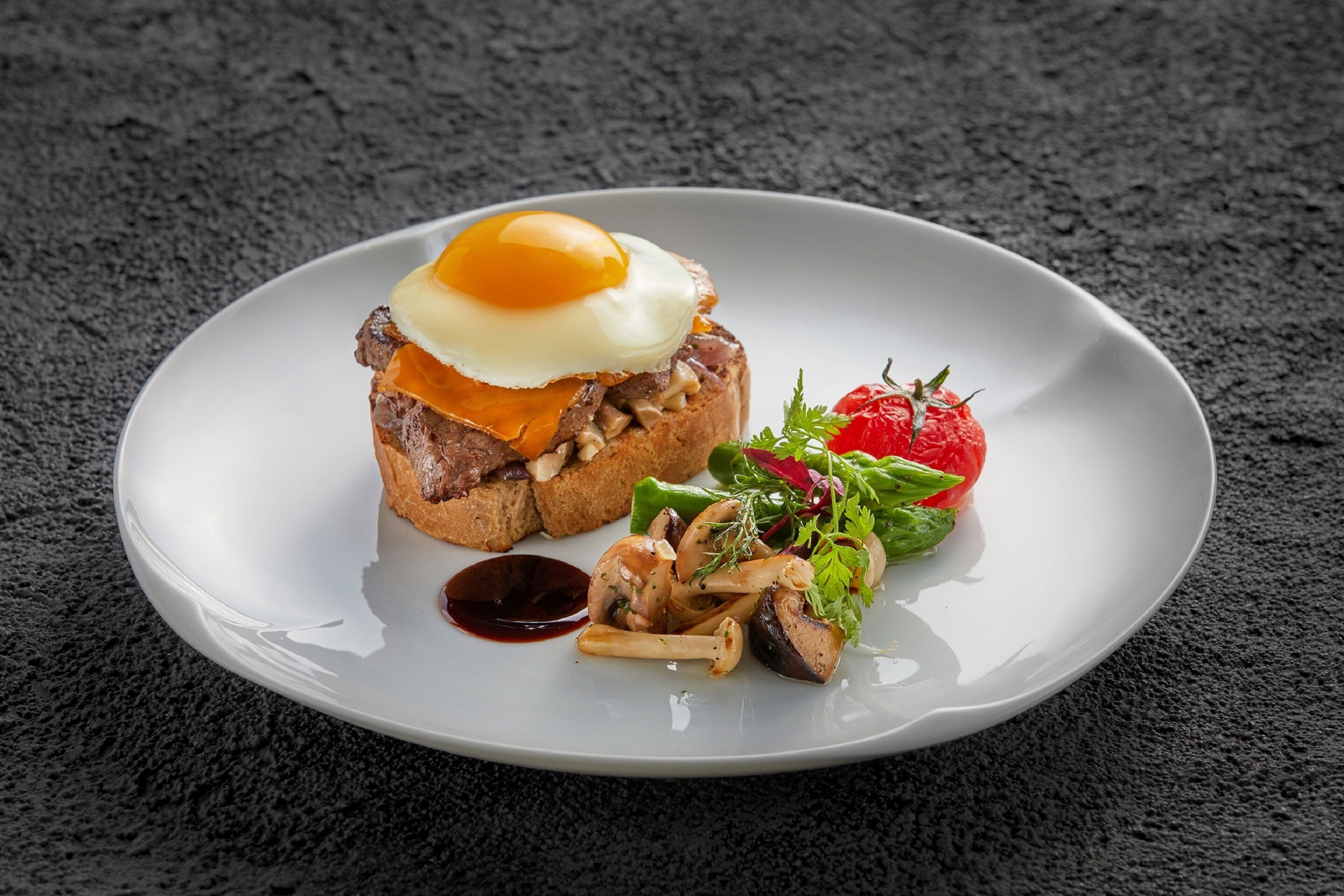 Une assiette avec un sandwich, un œuf poché et une salade en accompagnement.