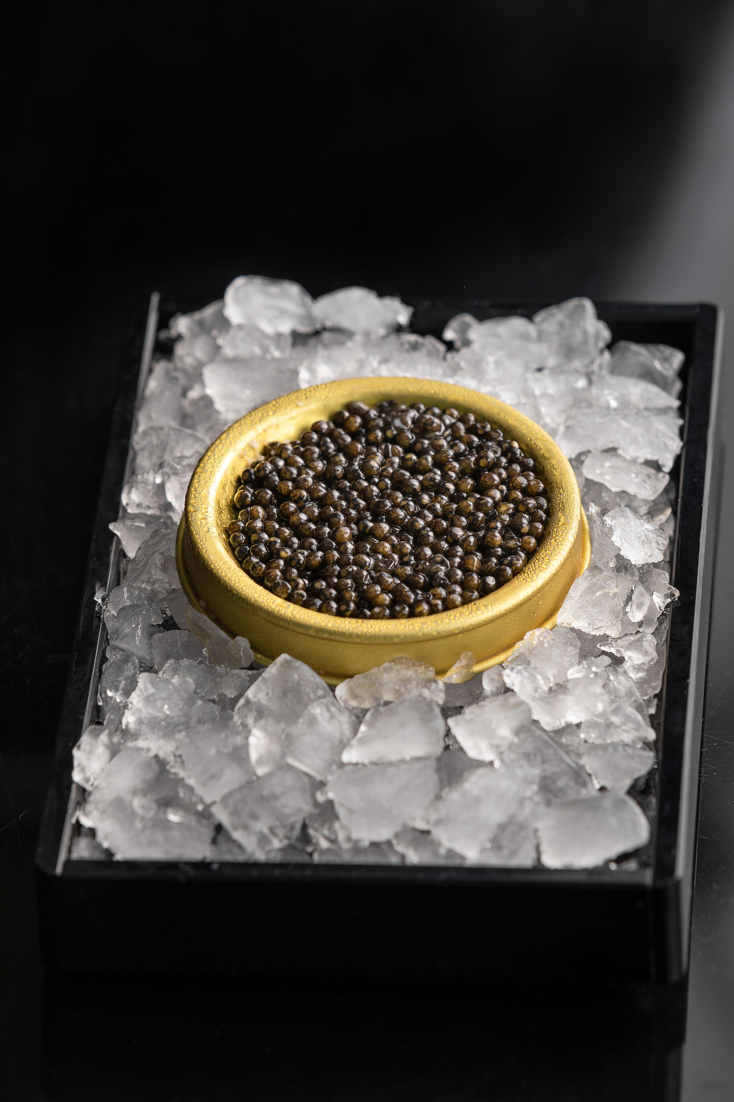 A bowl of caviar on ice cubes.
