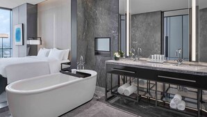 Un baño moderno con una bañera independiente, un espejo grande y un lavamanos con un estante para toallas.