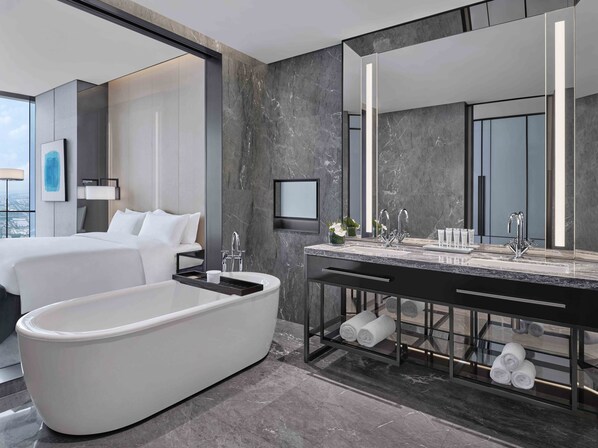 Un baño moderno con una bañera independiente, un espejo grande y un lavamanos con un estante para toallas.