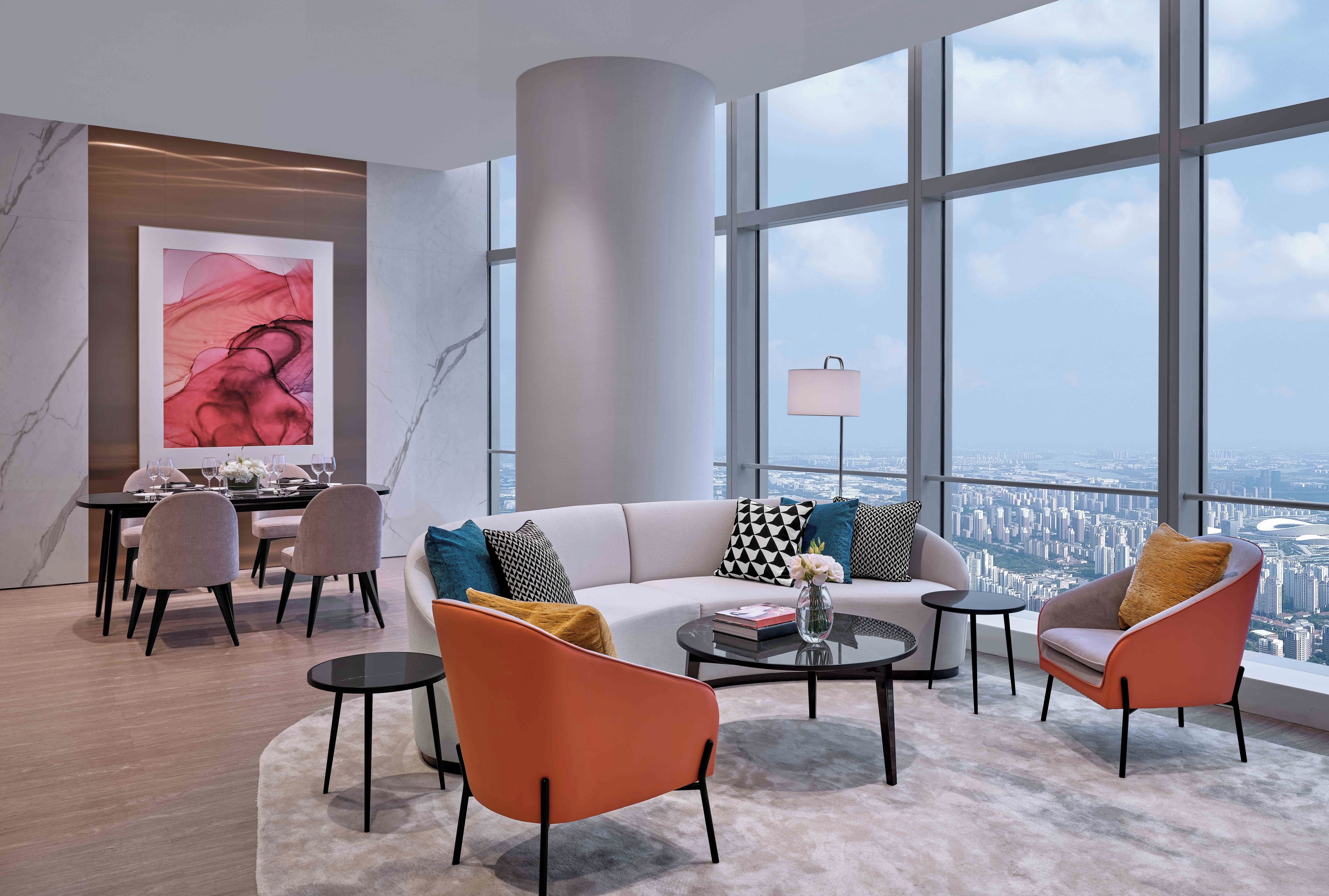 Ein modernes Wohnzimmer mit Blick auf die Stadt, einem Essbereich und einem großen abstrakten Gemälde.