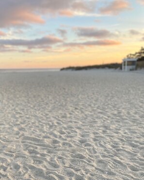 Una playa con cielo despejado y una torre de salvavidas a lo lejos.