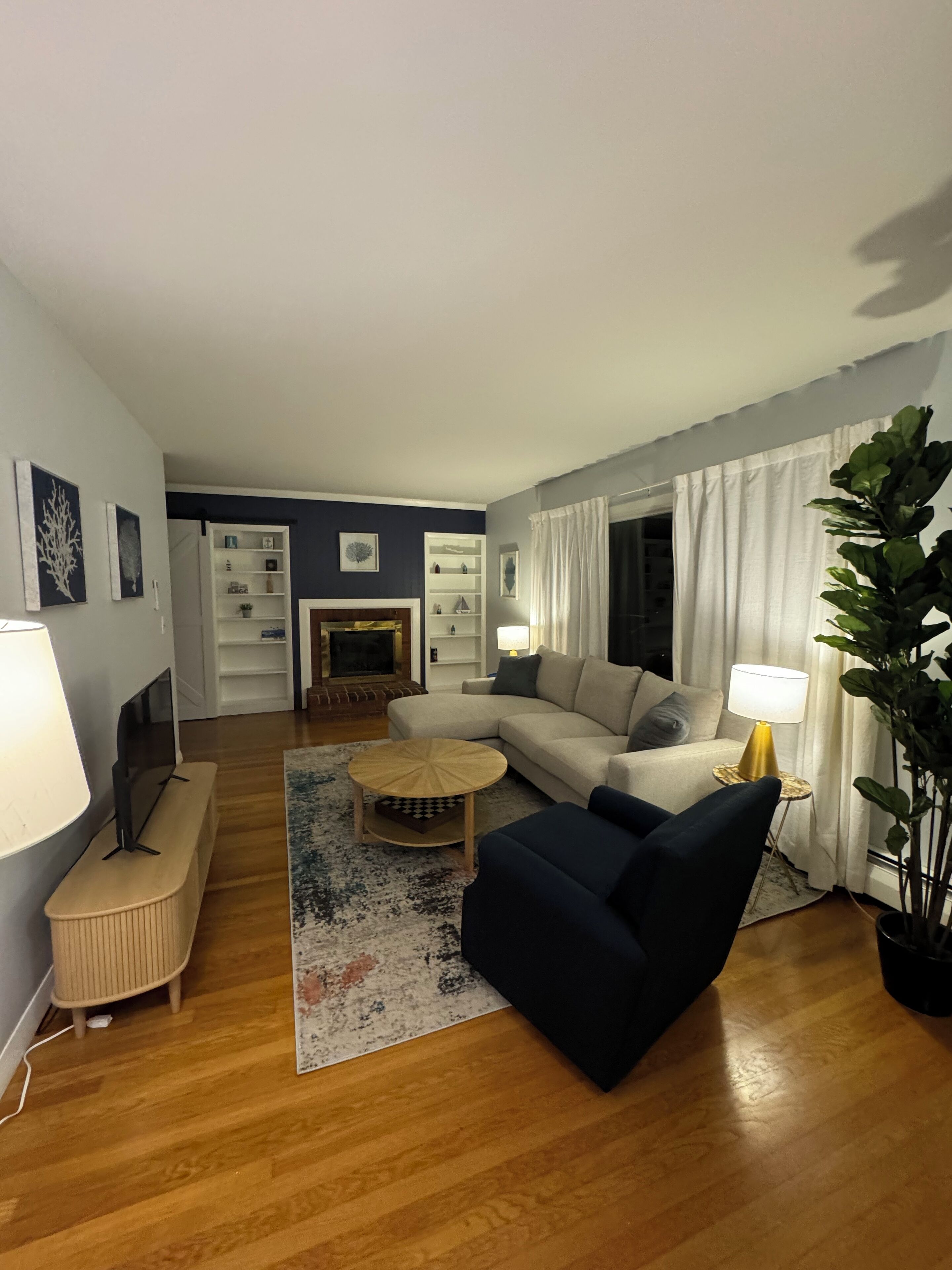 Una sala de estar con sofá, sillón, mesa de centro y chimenea.
