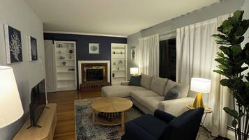 Una sala de estar con sofá, sillón, mesa de centro y chimenea.