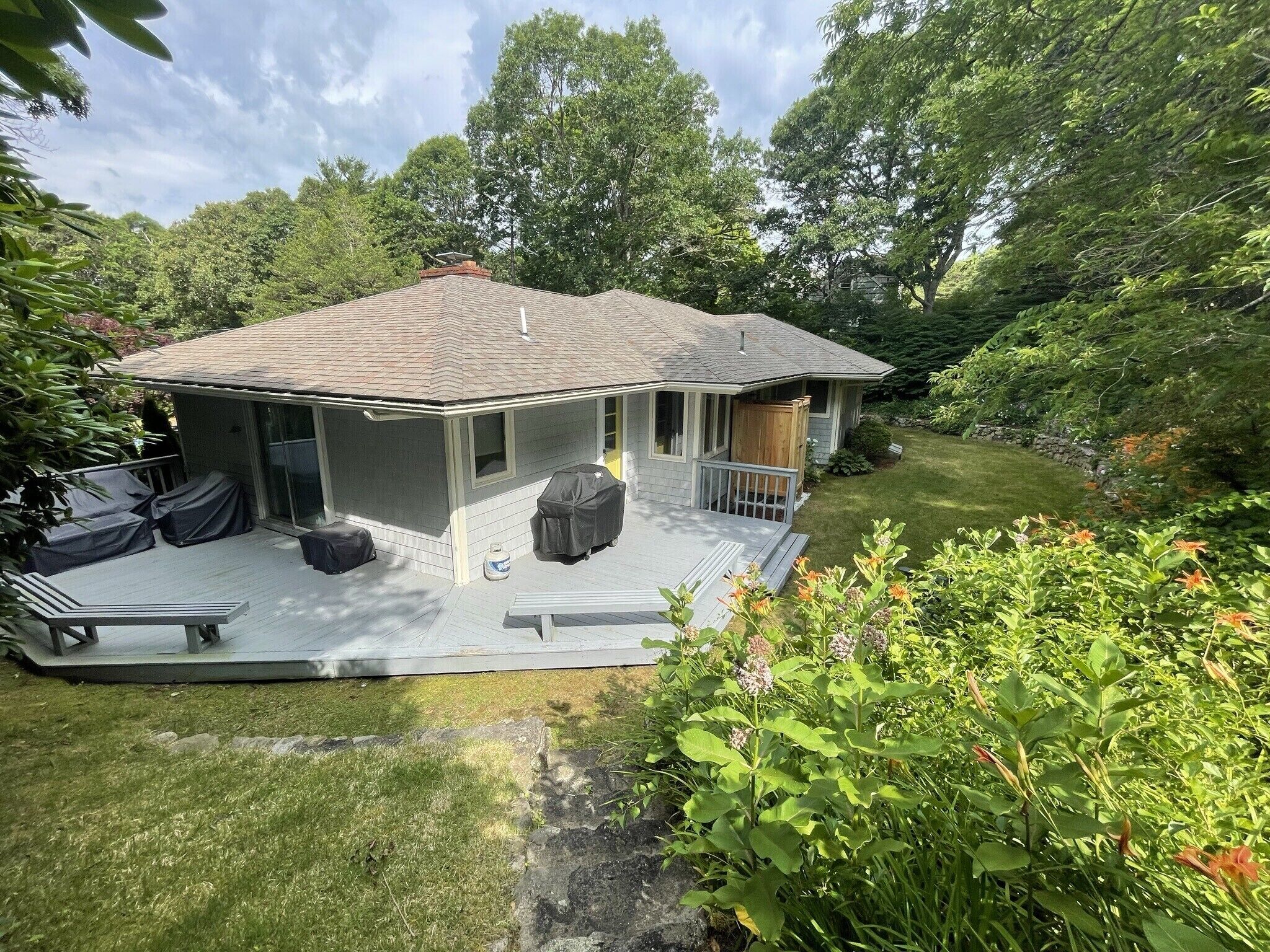 A house with a covered patio, a barbecue grill, and a lawn.