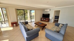 A living room with two sofas, a coffee table, a TV, and a balcony.