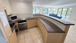 A modern kitchen with a curved countertop, built-in appliances, and a view of the outdoor balcony.
