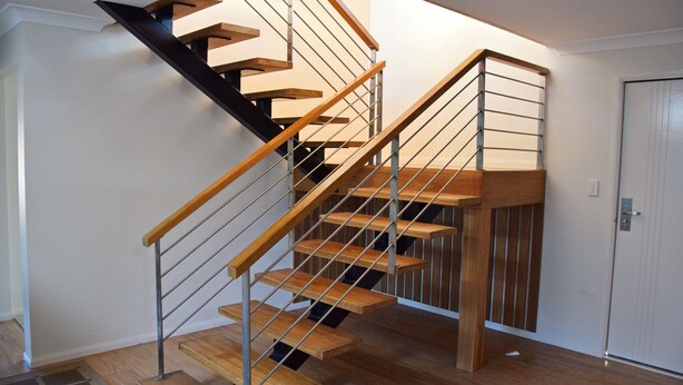 A modern staircase with wooden steps and metal railings, leading to a landing with a door. - Amberlee House - South West Rocks (SOUTH WEST ROCKS)