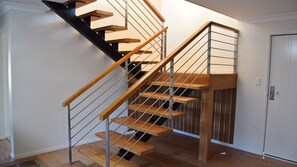 A modern staircase with wooden steps and metal railings, leading to a landing with a door.