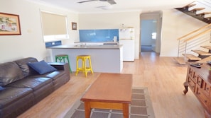 A modern apartment with a living room, kitchen, and staircase.