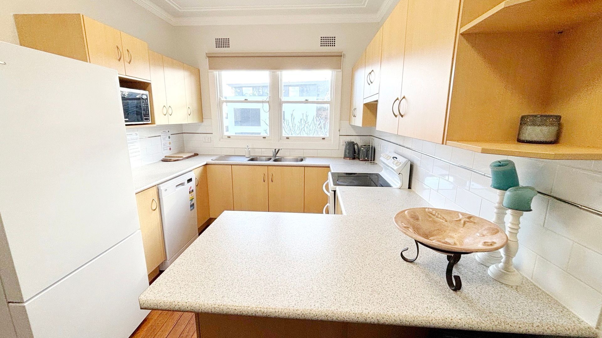 A kitchen with wooden cabinets, a white countertop, a sink, and a window.