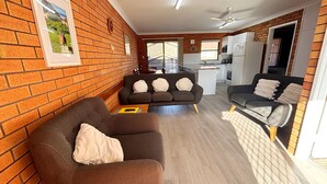 Un espacio habitable compacto con pared de ladrillo, un sofá, zona de comedor y kitchenette.