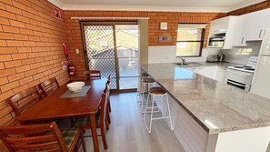 A kitchen with a dining area, a fire extinguisher, and a view through a glass door.
