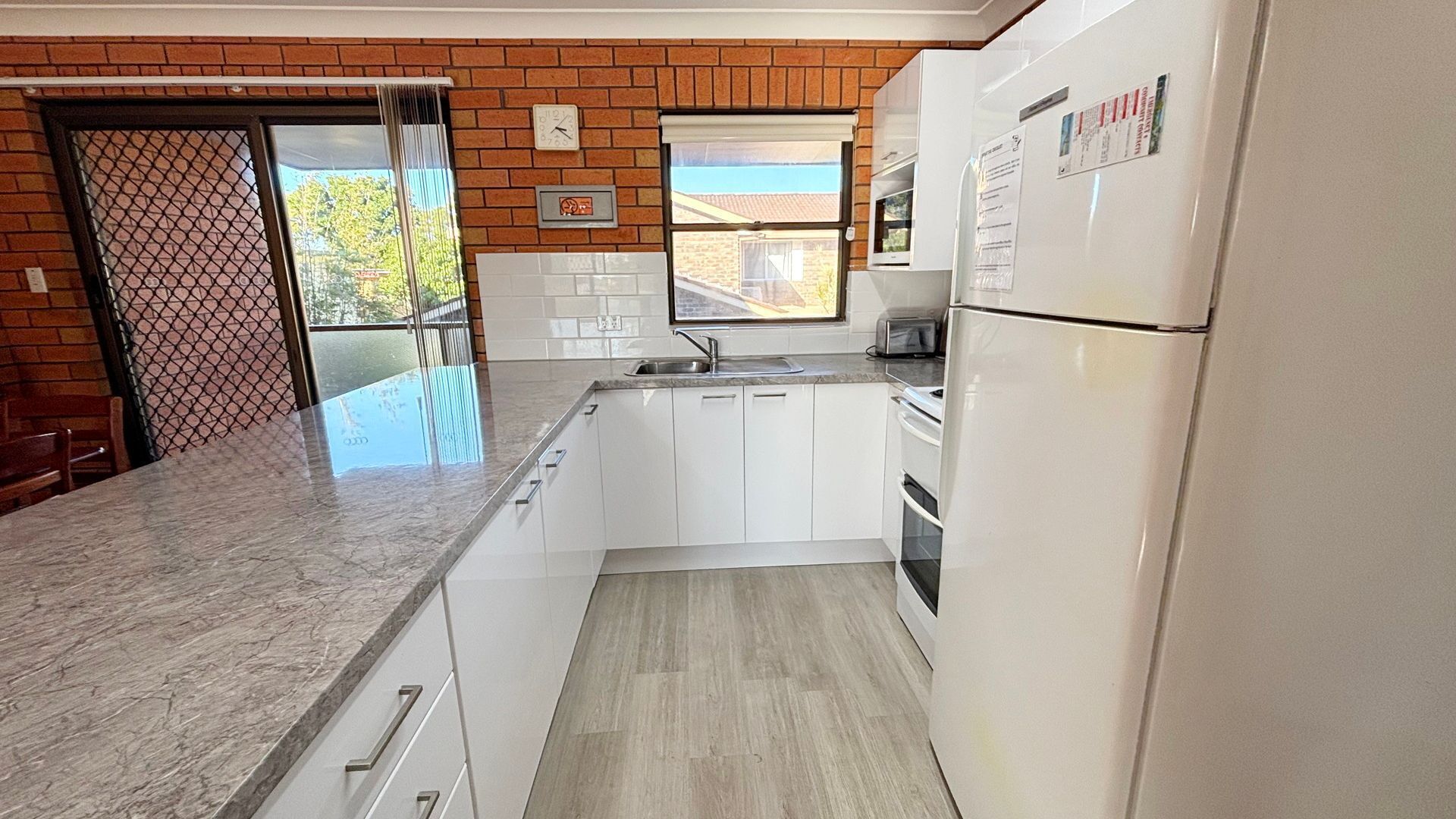A kitchen with white cabinets, a stainless steel sink, and a refrigerator.