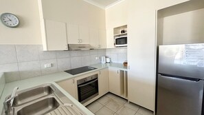 A modern kitchen with a stainless steel refrigerator, a microwave, a built-in oven, and a sink.