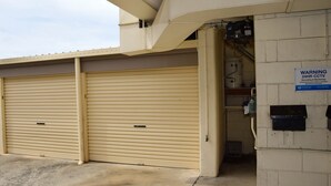 A closed garage door with a warning sign for 24-hour CCTV surveillance. - Ocean View 1 - South West Rocks - Bring your own linen (SOUTH WEST ROCKS)