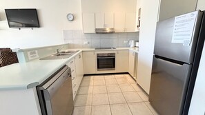 A compact kitchen with a built-in dishwasher, oven, and a refrigerator. - Ocean View 1 - South West Rocks - Bring your own linen (SOUTH WEST ROCKS)
