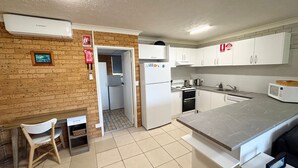 A compact kitchen with white cabinets, a built-in oven, and a microwave. - Seacrest # 5  - South West Rocks (SOUTH WEST ROCKS)