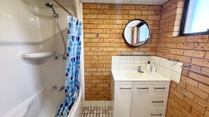 A bathroom with a bathtub, a shower, a sink, and a mirror. - Seacrest # 5  - South West Rocks (SOUTH WEST ROCKS)