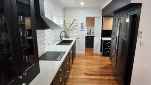 Een moderne keuken met zwarte kastjes, een wit aanrecht en een houten vloer.
