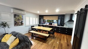 A compact kitchen with a dining area, wooden flooring, and black cabinetry.