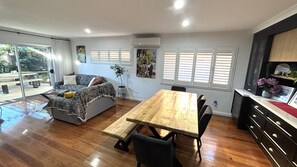 A spacious living area with a sofa, a wooden dining table, and a kitchen area with cabinets and a countertop.