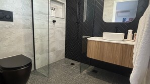 A modern bathroom with a toilet, a shower, and a sink.