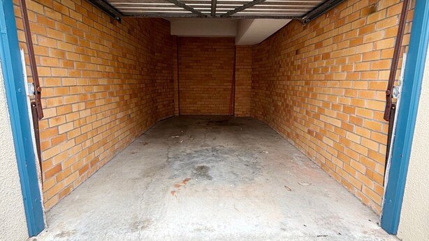Un espace étroit et clos, avec des murs en briques et un sol en béton, vraisemblablement une pièce servant d’abri ou de débarras.