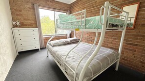 A bunk bed in a room with a brick wall, a window, and a white dresser. - Woody Wonder Unit 2 - South West Rocks (SOUTH WEST ROCKS)