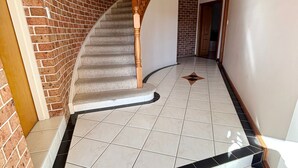A staircase with a wooden handrail leading to a door, surrounded by a brick wall and a tiled floor. - Horizons - South West Rocks - Bring your own linen (SOUTH WEST ROCKS)