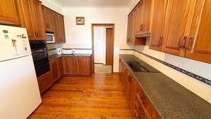 A kitchen with wooden cabinets, a refrigerator, a microwave, and a countertop. - Horizons - South West Rocks (SOUTH WEST ROCKS)