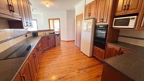 A kitchen with wooden cabinets, a refrigerator, an oven, and a microwave.