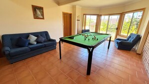 A room with a pool table, a blue sofa, and a chair. - Horizons - South West Rocks - Bring your own linen (SOUTH WEST ROCKS)