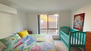 A bedroom with a bed, a crib, a window, and a painting on the wall. - Parkside # 1 - South West Rocks (South West Rocks)