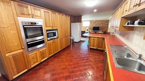 A kitchen with wooden cabinets, a stainless steel sink, and a red countertop.