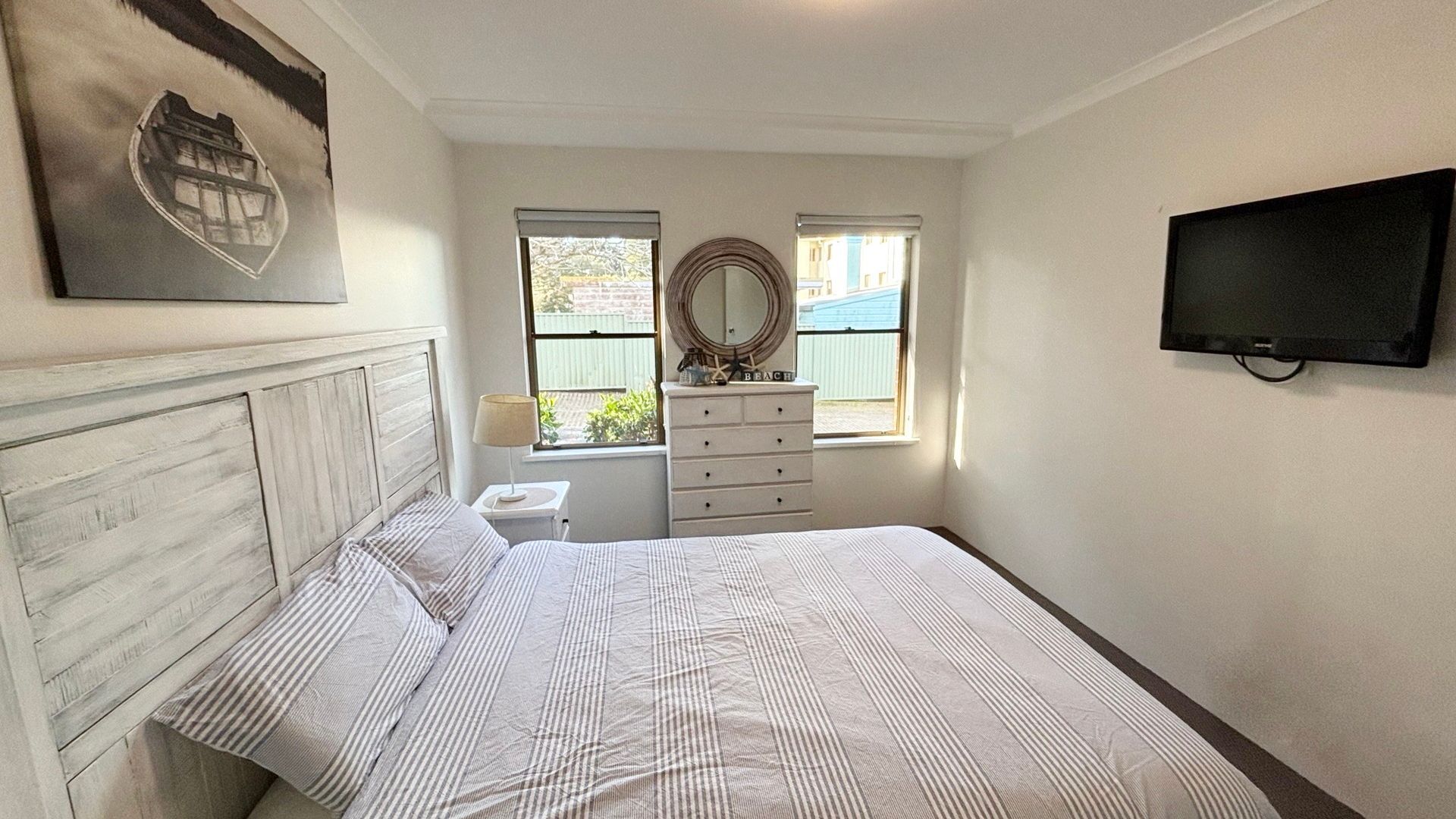 Een slaapkamer met een bed, een kaptafel, een spiegel en een televisietoestel.