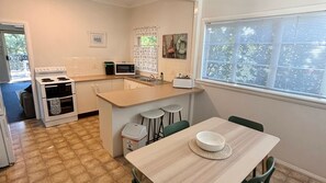 Una cucina compatta con fornello, forno a microonde, lavandino e sgabelli da bar.