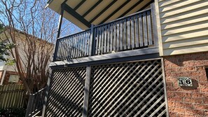 Ein zweistöckiges Gebäude mit einem Balkon, einem Metallgitter und einer Ziegelmauer mit einer Hausnummer.