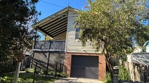 Ein zweigeschossiges Haus mit überdachter Veranda, Garage und umzäunter Garten.