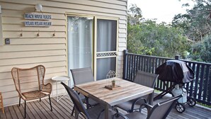 A wooden deck with a table and chairs, a grill, and a sign reading "BEACH HOUSE RULES" and "RELAX RELAX RELAX". - Susie's Beach House - South West Rocks (SOUTH WEST ROCKS)