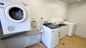 A laundry room with a front-loading washing machine, a dryer, and a steam iron. - Dunbar Court Unit 7 - Bring your own linen (SOUTH WEST ROCKS)